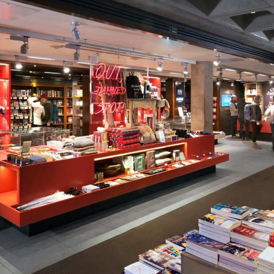 Bookshop Out Damned Spot Dec 2021 The Bookshop in the ground flooor foyer of the National Theatre, with tables and display cabinets of books and merchandise.