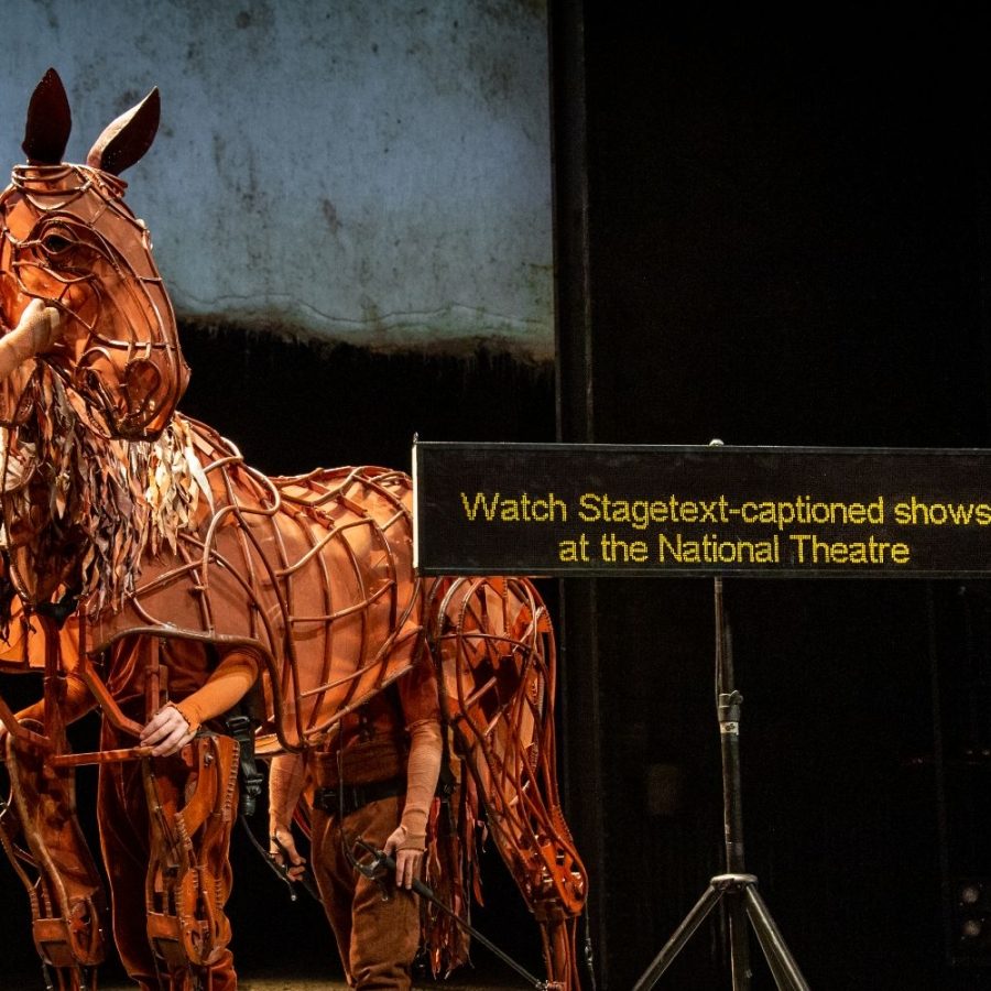 War Horse Stagetext-Captioning War Horse puppet and handlers and a Stagetext Caption screen with the message: Watch Stagetext-captioned shows at the National Theatre.