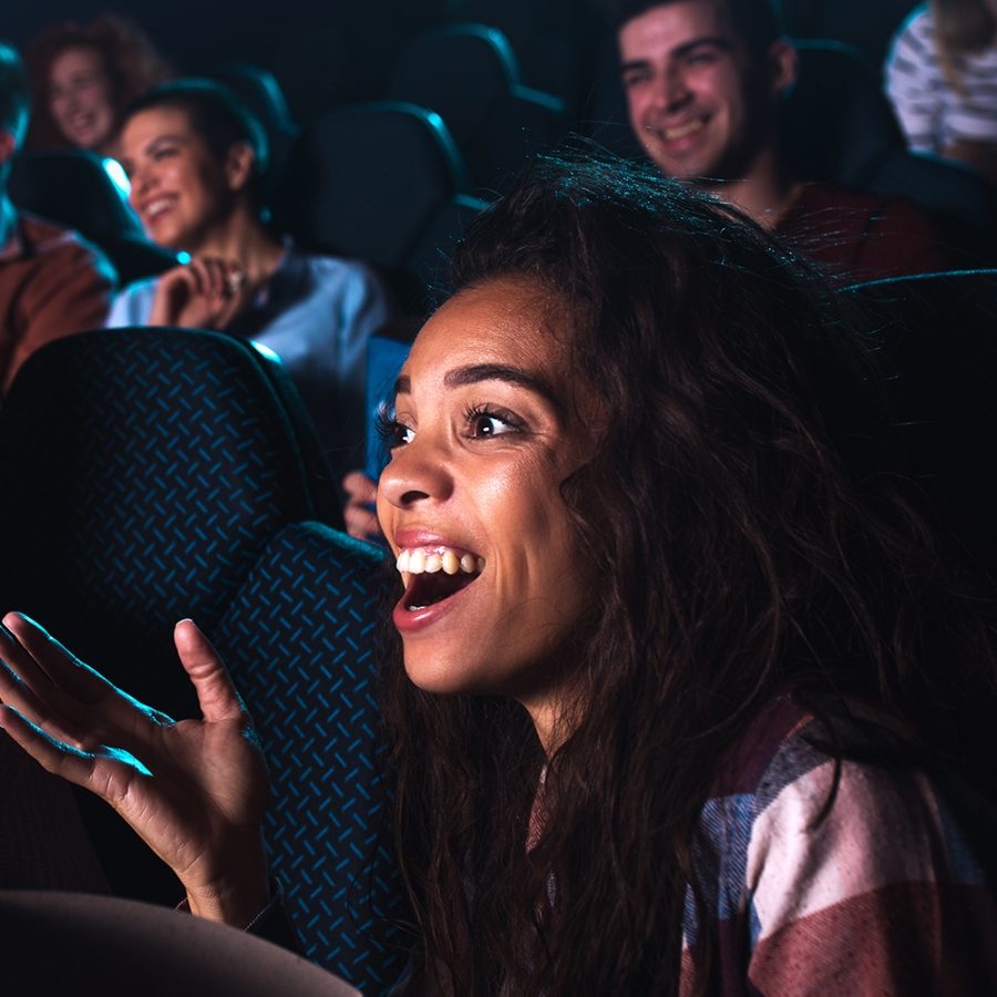 Close-up of people seated in an auditorium, laughing in response to a performance.