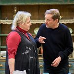 Siobhán McSweeney and Ardal O'Hanlon in conversation with one another. Siobhán is wearing a red shirt and black jumpsuit. Ardal is wearing a black jumper.