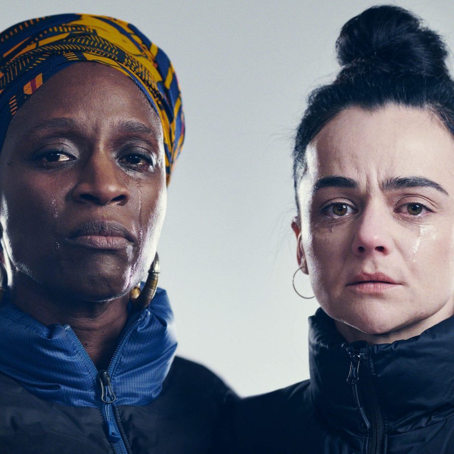 A close-up of the faces of two women, both looking sad, with tears in their eyes and rolling down their cheeks.