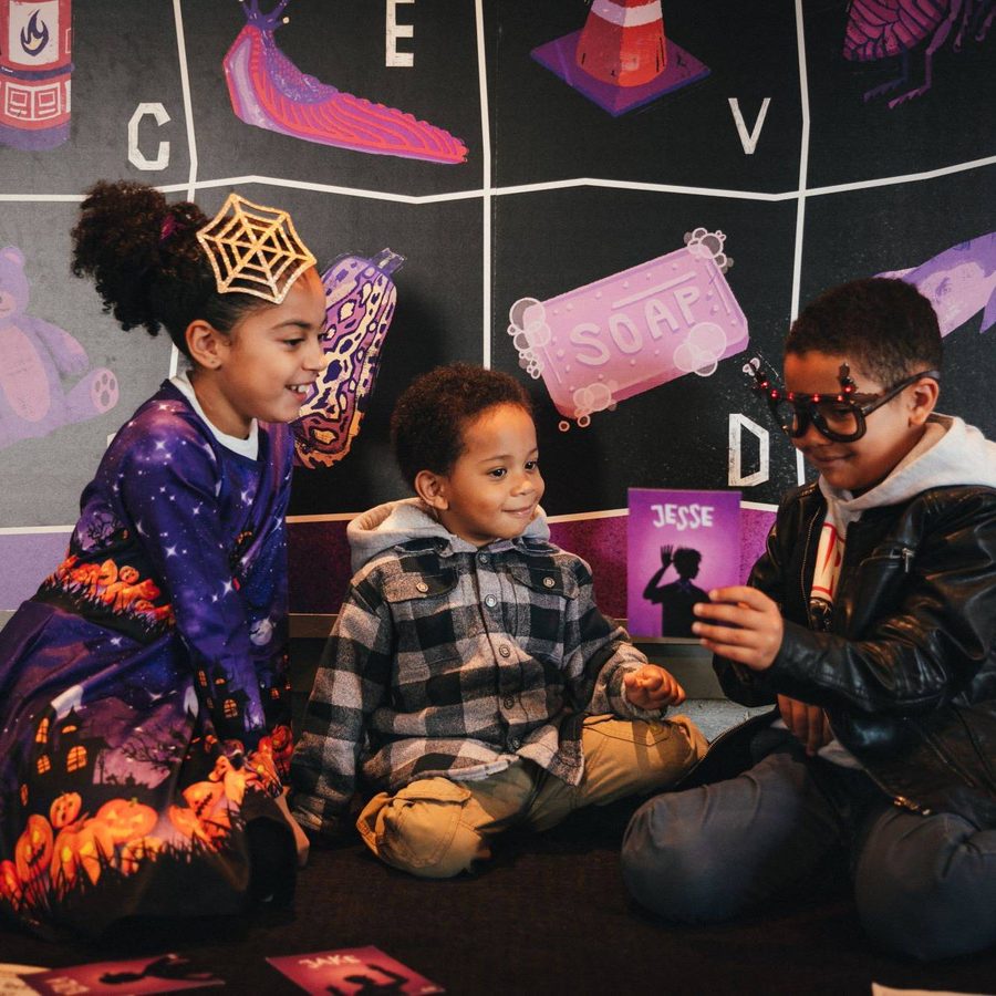 A group of children are sitting on the floor over an activity pack.